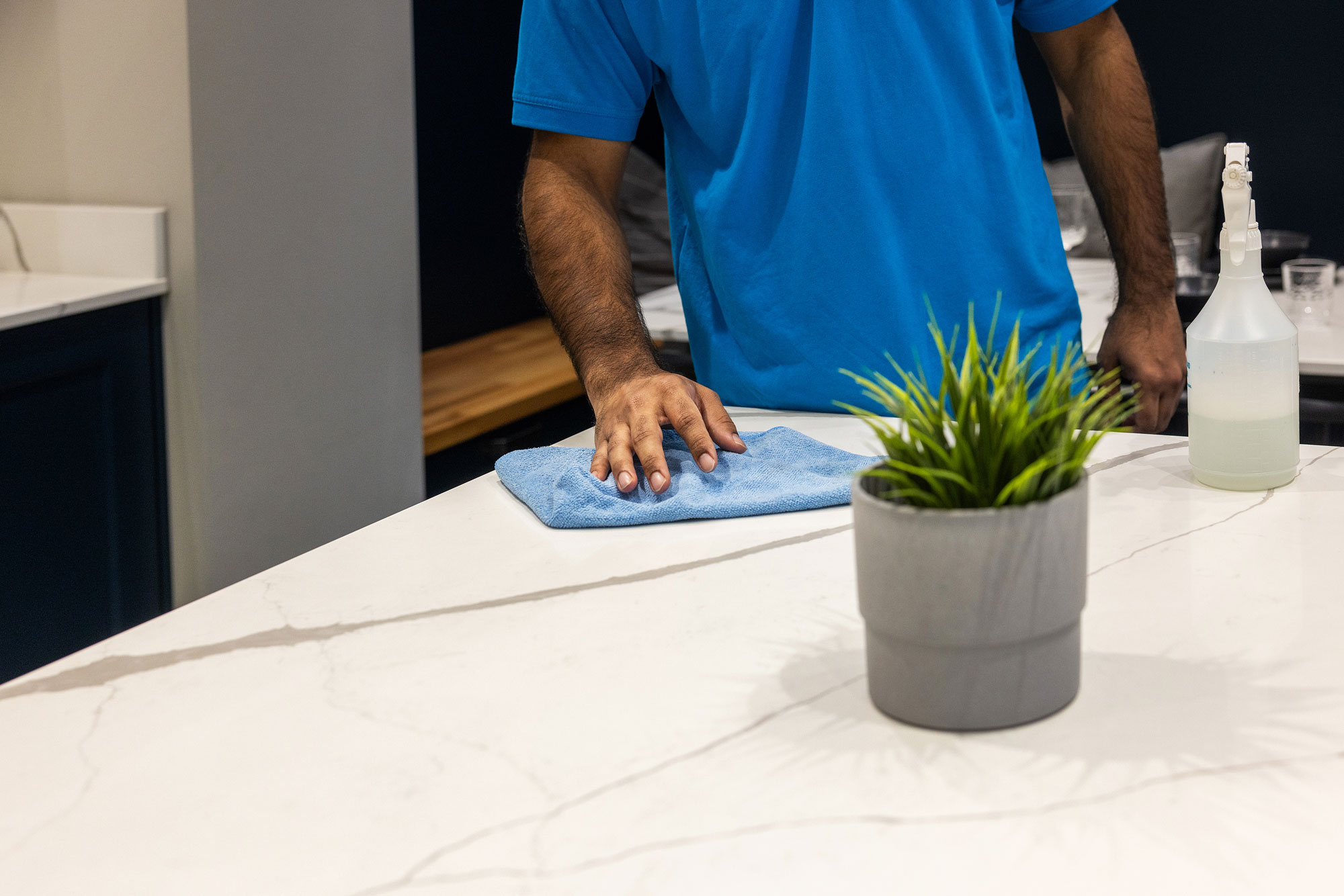cleaner cleaning quartz worktop with blue cloth