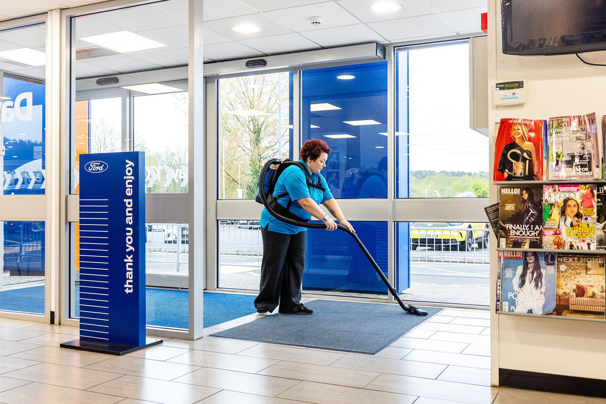 female cleaner cleaning with pac vac in car showroom